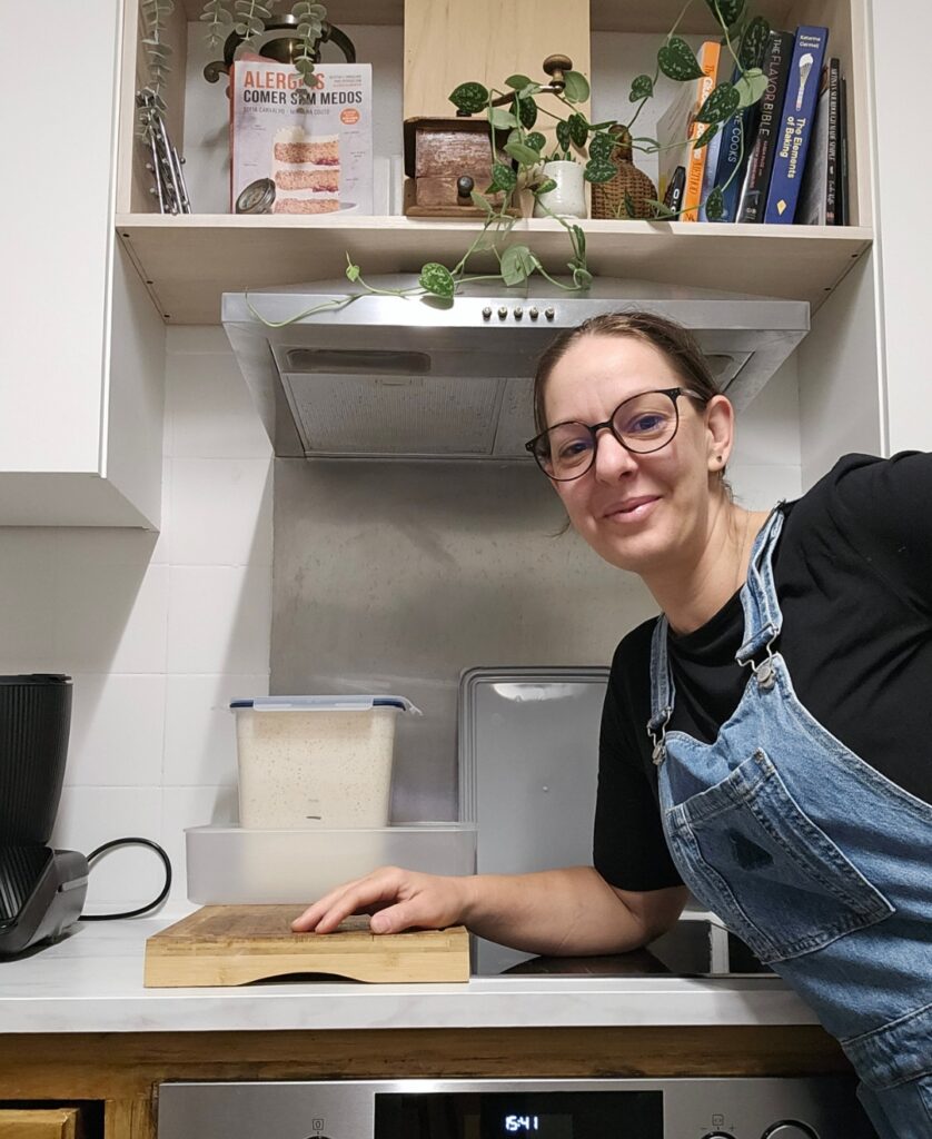 Sofia Carvalho na sua cozinha, ao lado de uma caixa com fermento natural crescido quase a transbordar
